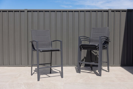 PERO Outdoor Bar Chair - Gunmetal (Set of 4) on a light porcelain paved terrace.