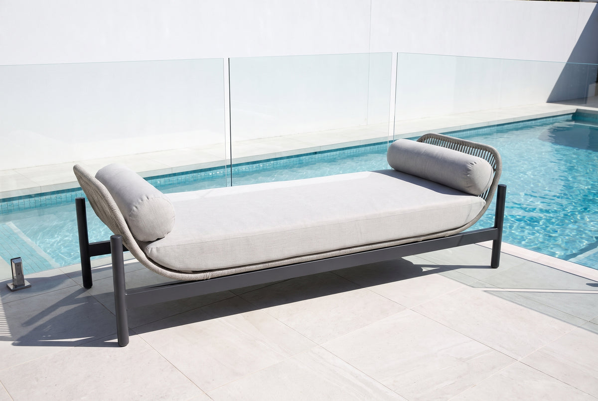 COSTA Outdoor Daybed beside a pool on a light porcelain paved terrace