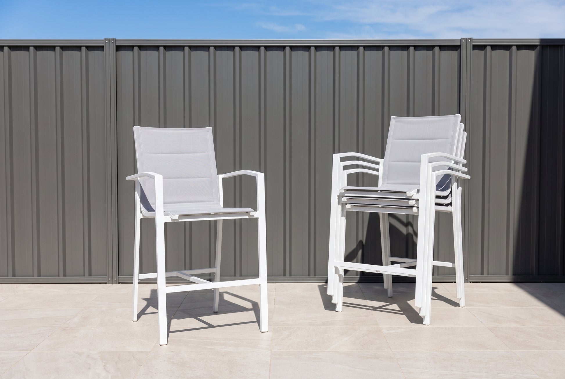 PERO Outdoor Bar Chair - White (Set of 4) on a light porcelain paved terrace.