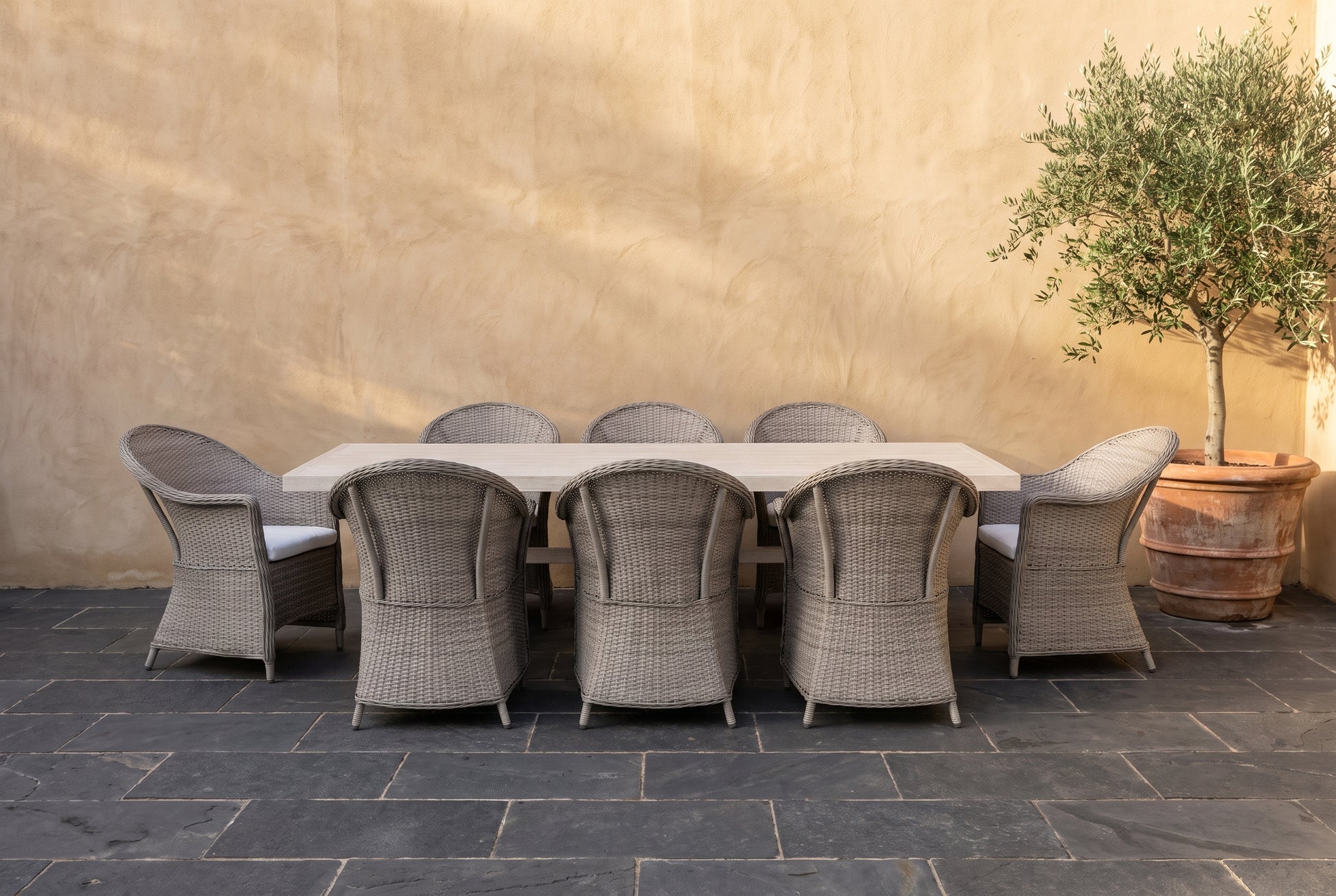 ZINNIA IX 8-Seater Outdoor Dining Setting on a dark charcoal stone paved terrace